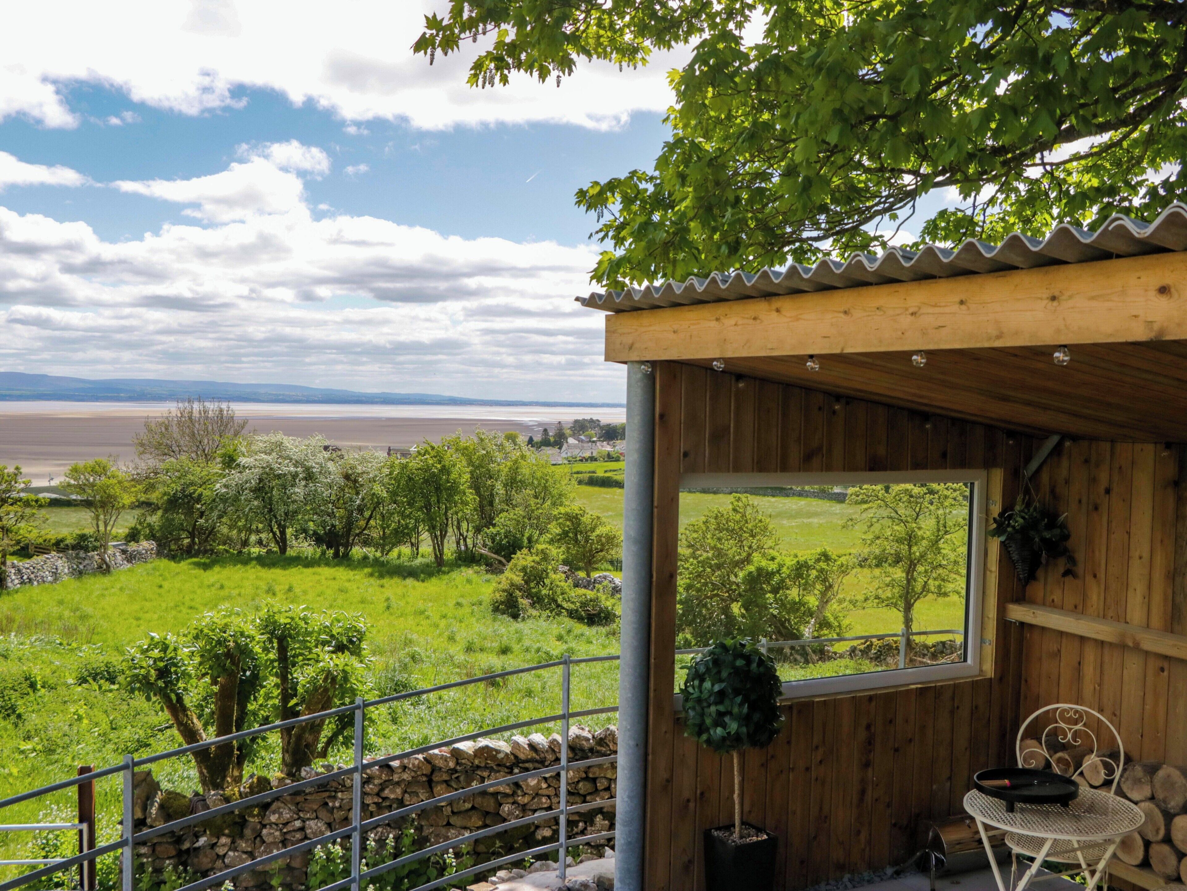 A wooden cabin with a view of a lake and hills.
