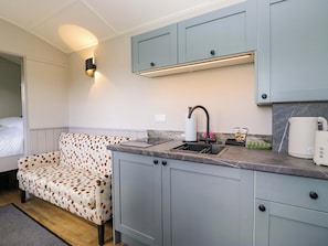 A compact kitchenette with a built-in stove, a sink, and a coffee maker. - Little Hut (Grange-over-Sands)