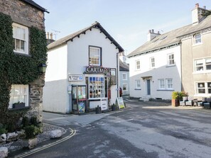 A white building with a sign reading 'CARTME' and a Village Hall sign. - Little Hut (Grange-over-Sands)