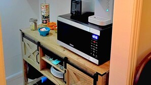 Eine kleine Küche mit Kaffeemaschine, Mikrowelle und einer Ablage für Küchenutensilien.