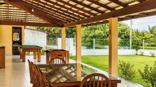 Un espacio al aire libre techado con mesa de billar, sillas y mesa de comedor.