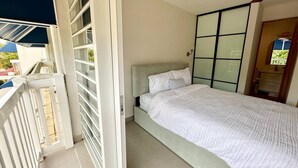Een slaapkamer met een bed, een raam en een balkon.