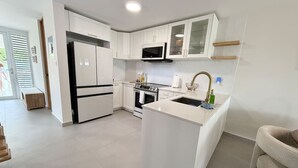 Een moderne keuken met witte kasten, een centraal eiland, een magnetron en een spoelbak.