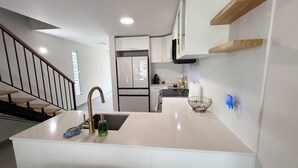 Een moderne keuken met een centraal eiland, witte keukenkastjes en een roestvrijstalen koelkast.