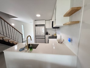 A modern kitchen with a central island, white cabinetry, and a stainless steel refrigerator. - Beachfront, Ocean Views & Renovated Spaces (Dorado)