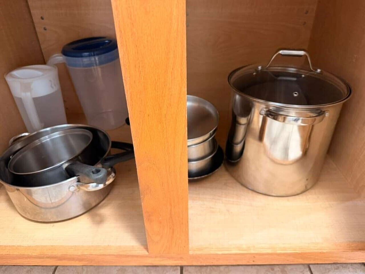 Una estantària de cuina amb menjar i utensilis de cuina d'acer inoxidable, incloent-hi cassoles i paelles.