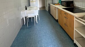 Una cucina piccola con un tavolo da pranzo e sedie, un frigorifero, un forno a microonde e pensili in legno.