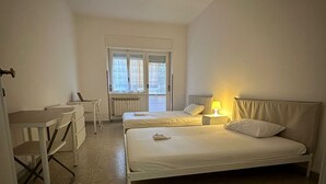 Una camera da letto con un letto, una scrivania, una sedia, una lampada e una finestra.