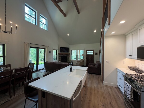 A spacious kitchen with a large island, wooden flooring, and a dining area with a table and chairs.