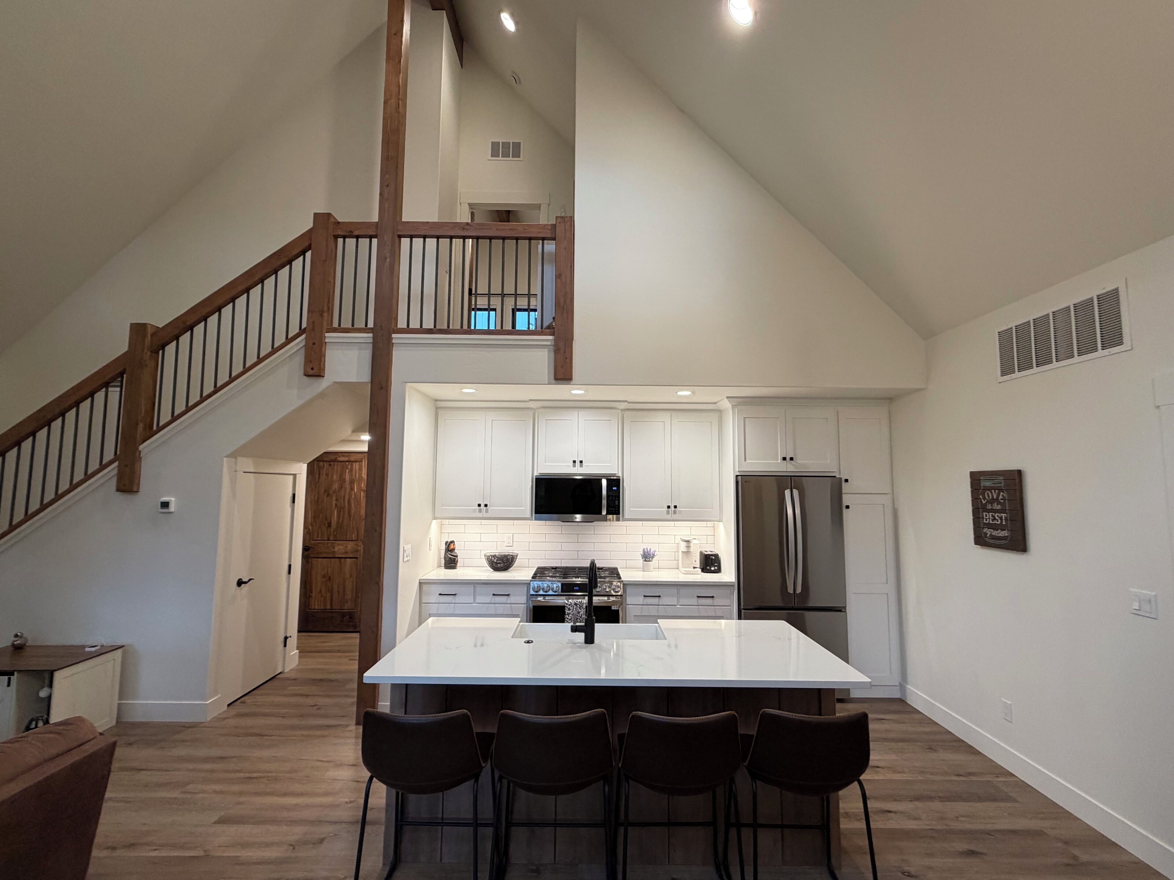 A spacious kitchen with a central island, white cabinetry, and a stainless steel refrigerator.