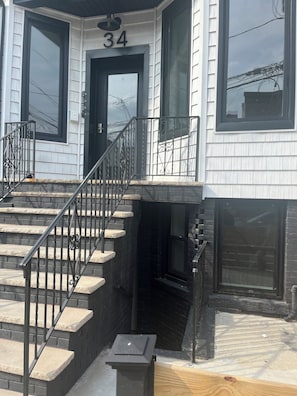 A two-story house with a black front door, a number '34' above the door, and a staircase with black railings leading to the second floor.
