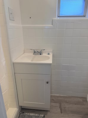 A bathroom with a white sink, a mirror, and a window. - Patio Court Motel (Quakertown)