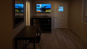 Una habitación con televisión, una mesa y una puerta.