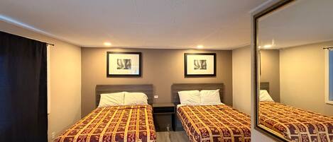 Ein Hotelzimmer mit zwei Betten, einem großen Spiegel und zwei gerahmten Bildern an der Wand.
