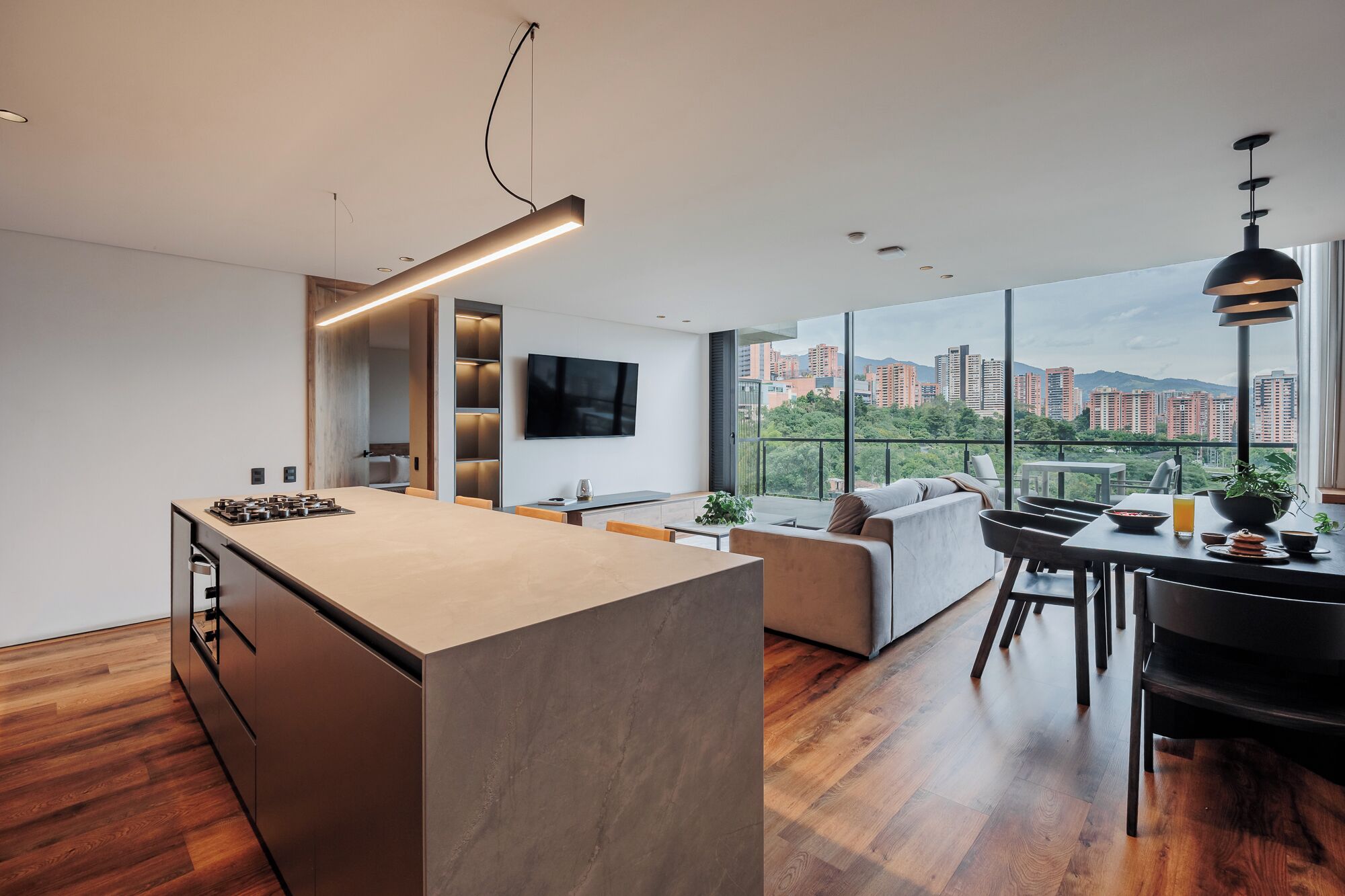 A modern kitchen with a large island, a dining area with a view, and a living space with a sofa and table.