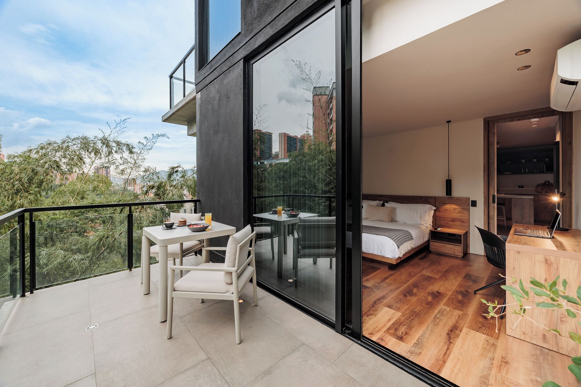 Um apartamento moderno com varanda, área de refeições e quarto com cama e escrivaninha.
