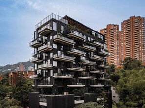 Een modern meerlaags gebouw met balkons, omringd door groen en andere gebouwen.