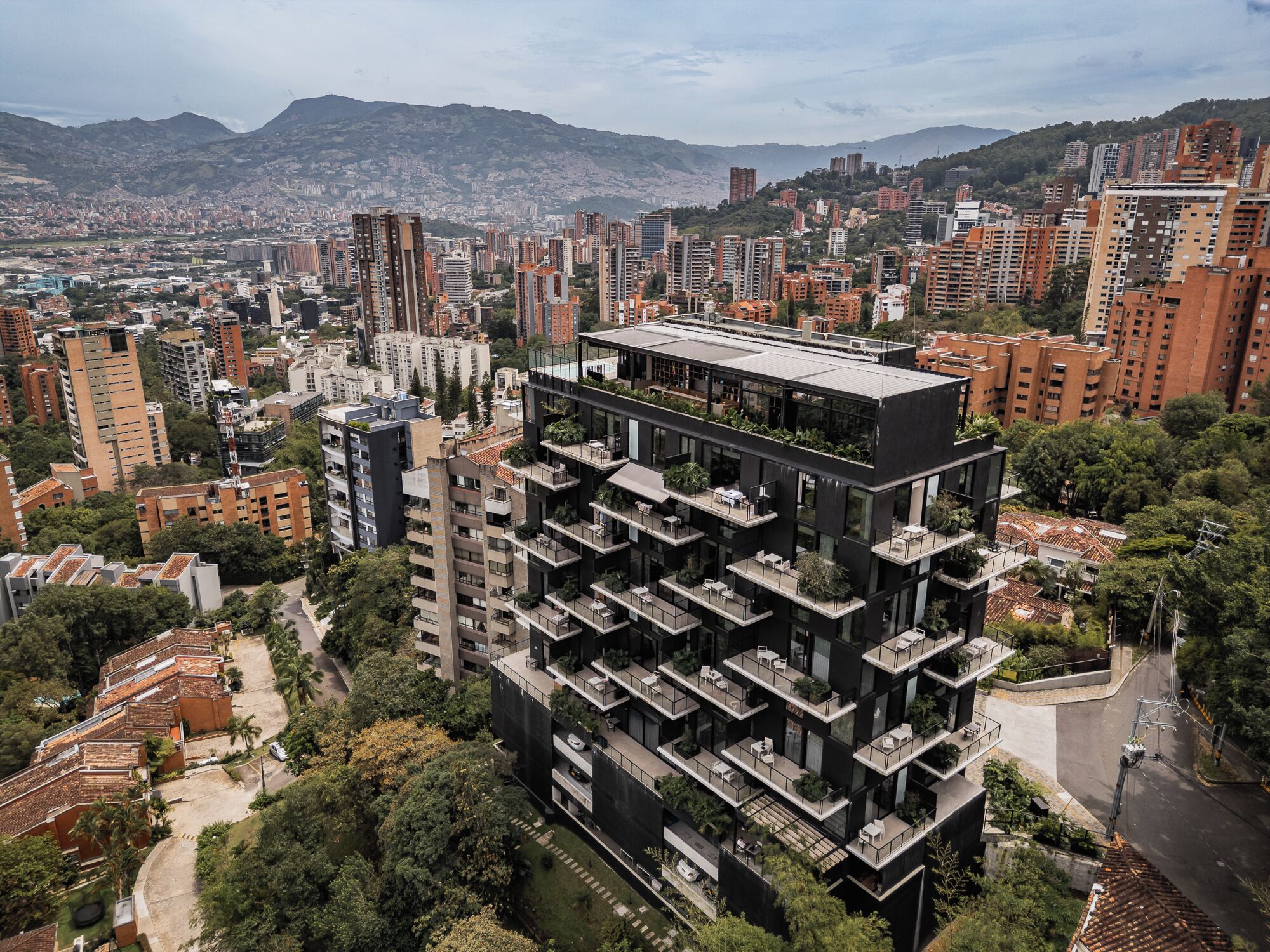 A high-rise building with multiple balconies, surrounded by a dense urban area with other high-rise buildings.