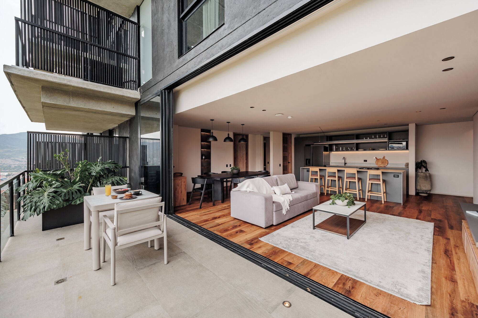 Apartamento moderno com área de refeições, cozinha e varanda com plantas.