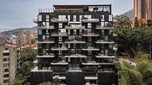 Un edificio a più piani con balconi, un giardino sul tetto e vista sull'area urbana circostante.