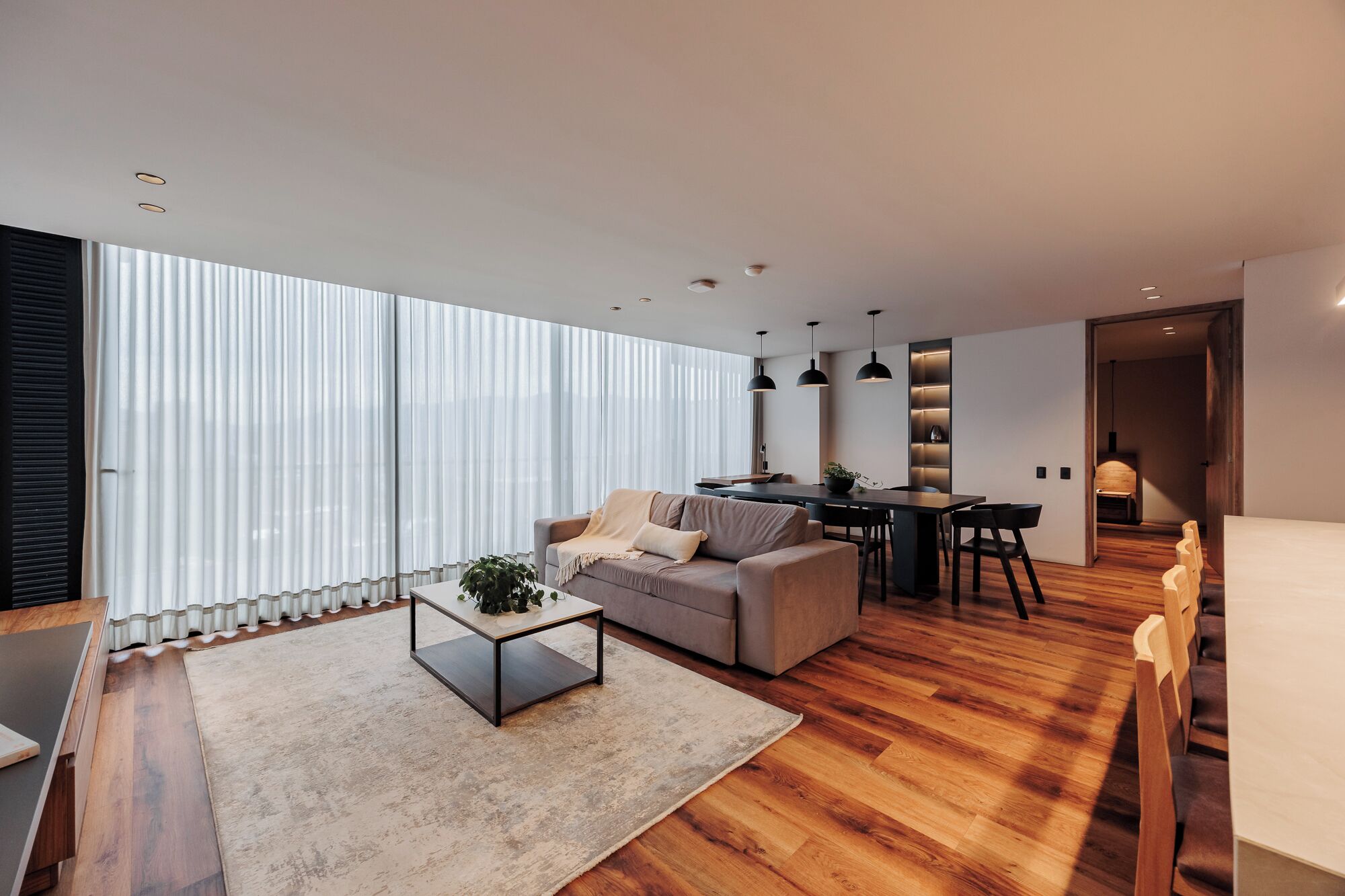 A modern living room with a sofa, coffee table, and dining area.
