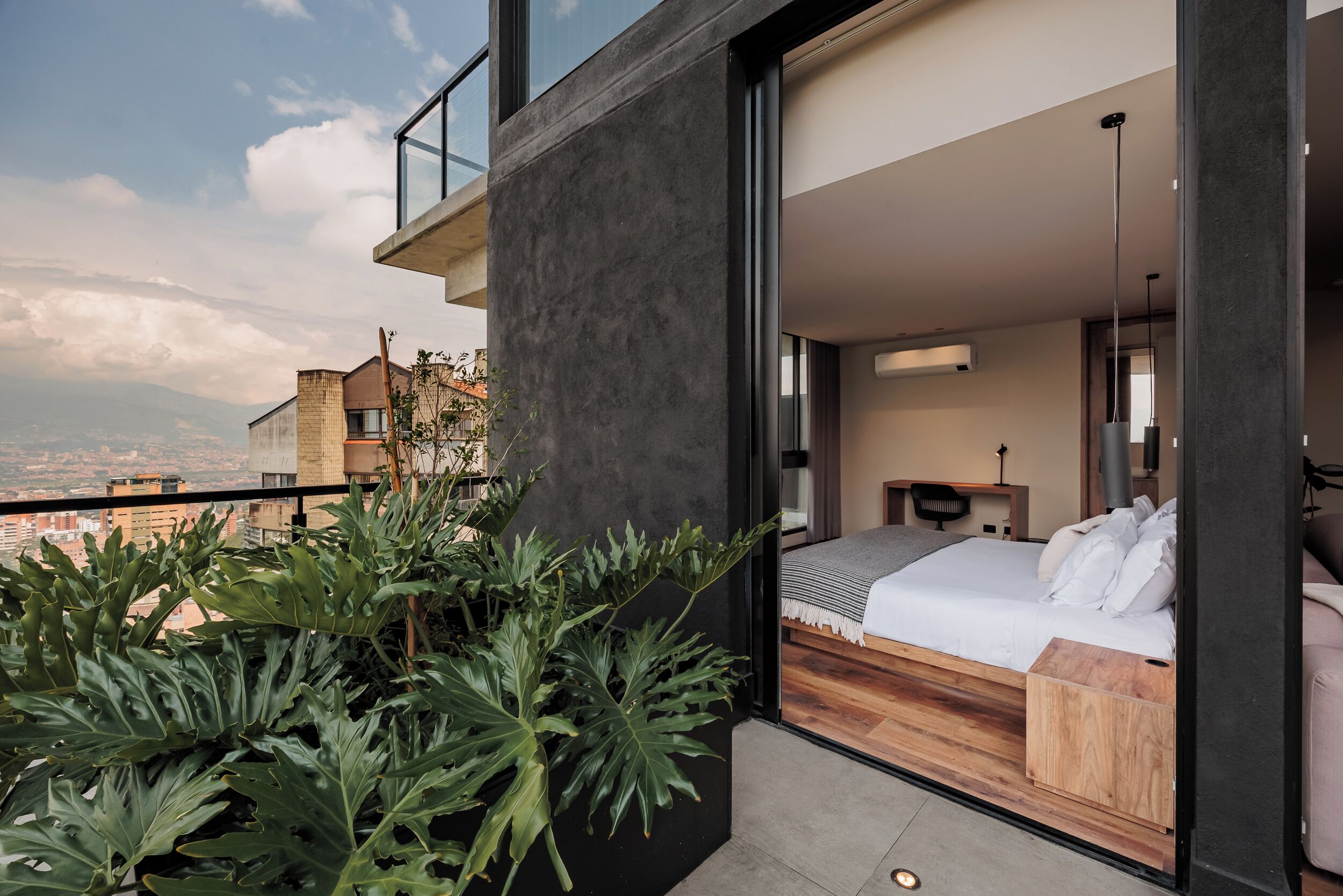 Un dormitorio moderno con una cama grande, una mesita de noche y vistas a la ciudad.