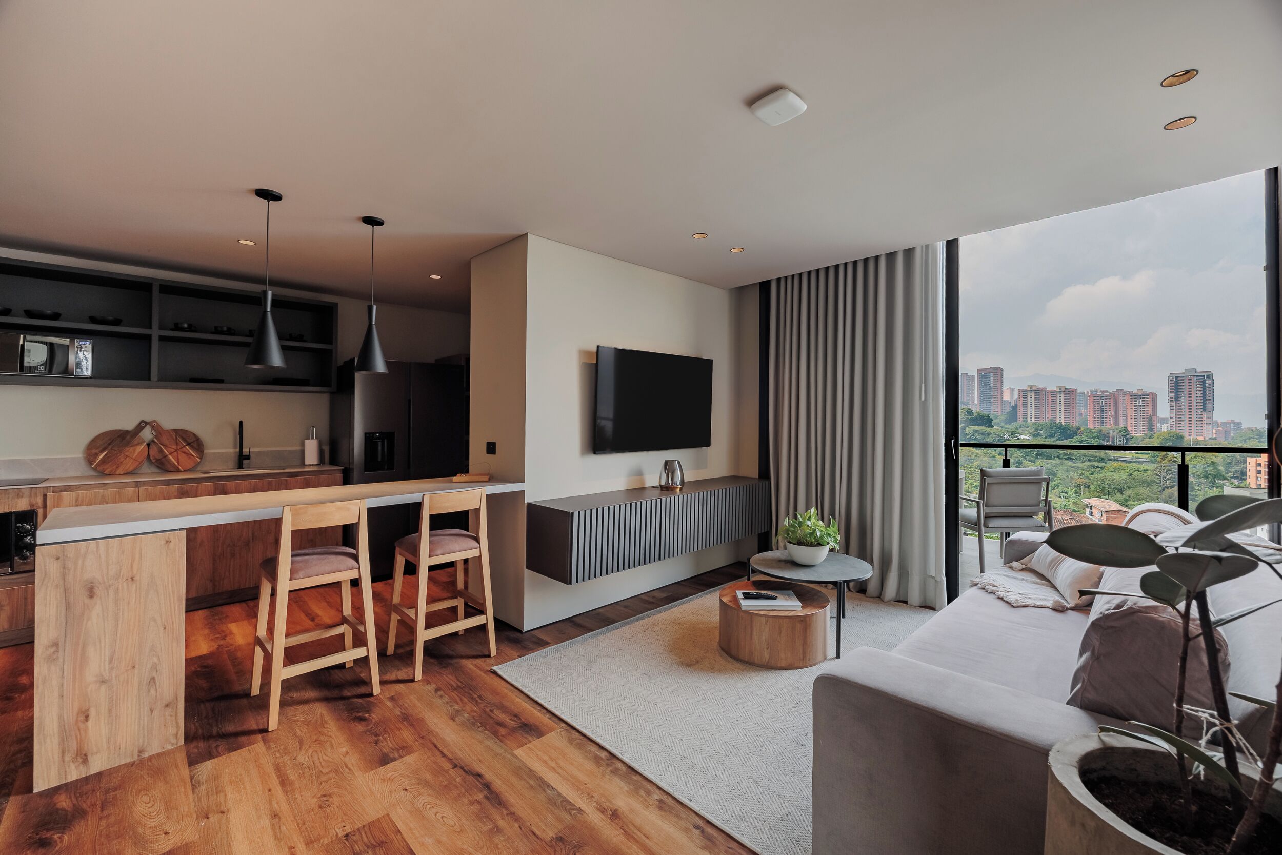 Un espacio habitable moderno con cocina, comedor y un ventanal con vistas a la ciudad.