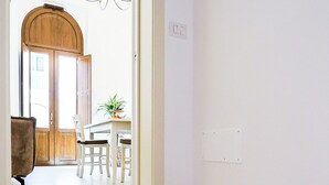 Ein modernes Interieur mit einem Glastisch im Vordergrund, einer Holztür und einem Essbereich im Hintergrund.