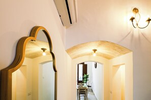 Un corridoio con uno specchio, un lampadario e un arco che dà accesso a una sala da pranzo.