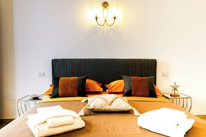 Un letto con una testiera scura, numerosi cuscini, un comodino con una lampada e una decorazione a stella marina.