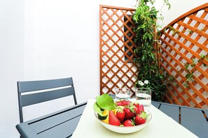 Un tavolo con una ciotola di frutta, due bicchieri e una sedia.