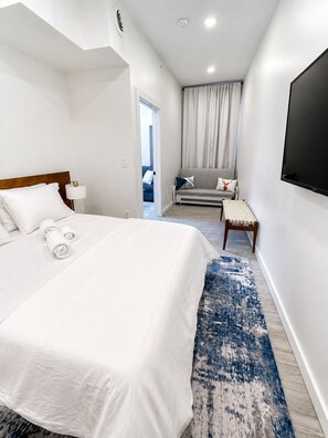 Ein Hotelzimmer mit einem großen Bett, einem an der Wand montierten Fernseher, einer Couch und einem kleinen Tisch.