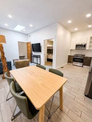 Eine moderne Wohnung mit Essbereich, Wohnzimmer, Küche und Fernseher.