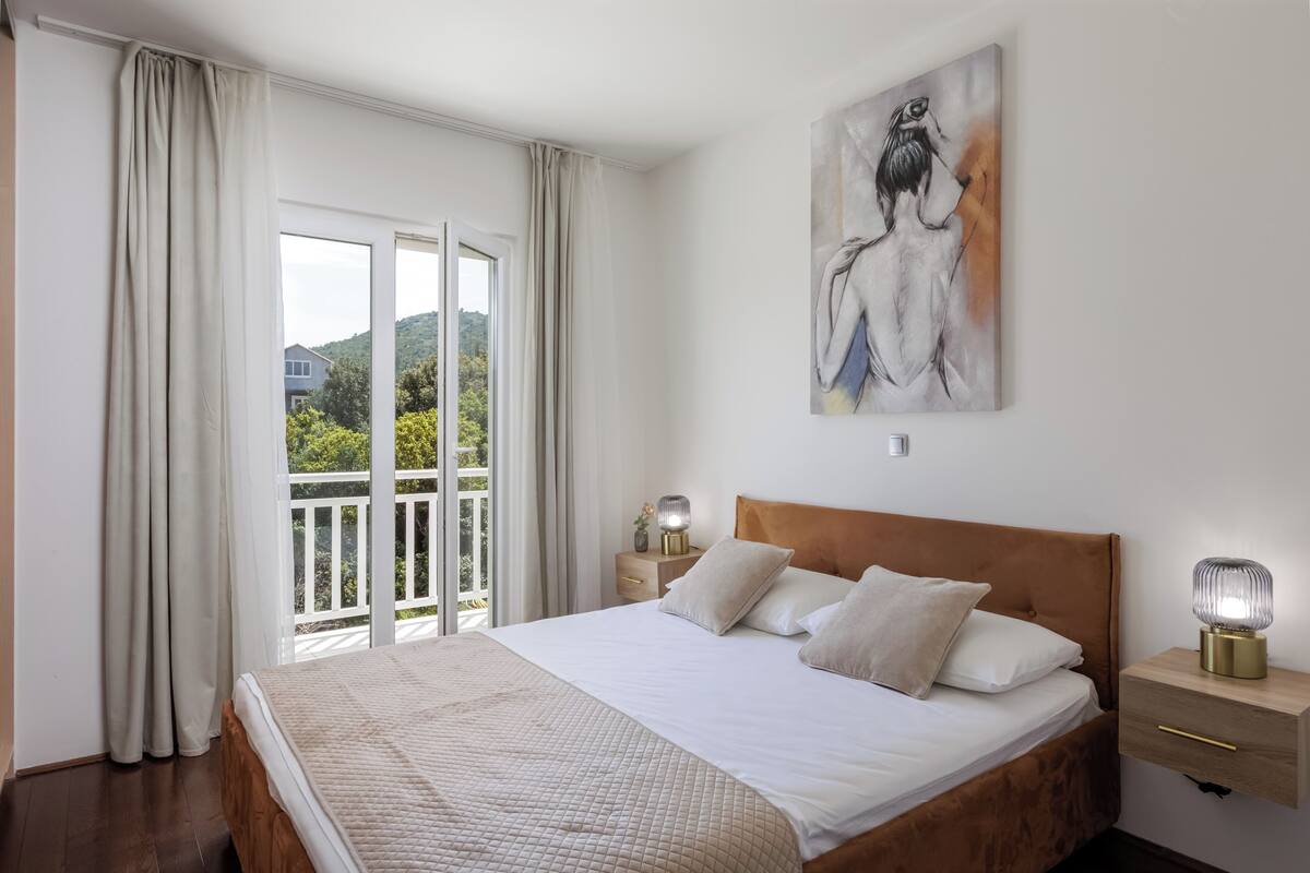 Un dormitorio con una cama grande, una mesita de noche, una lámpara y un cuadro en la pared.