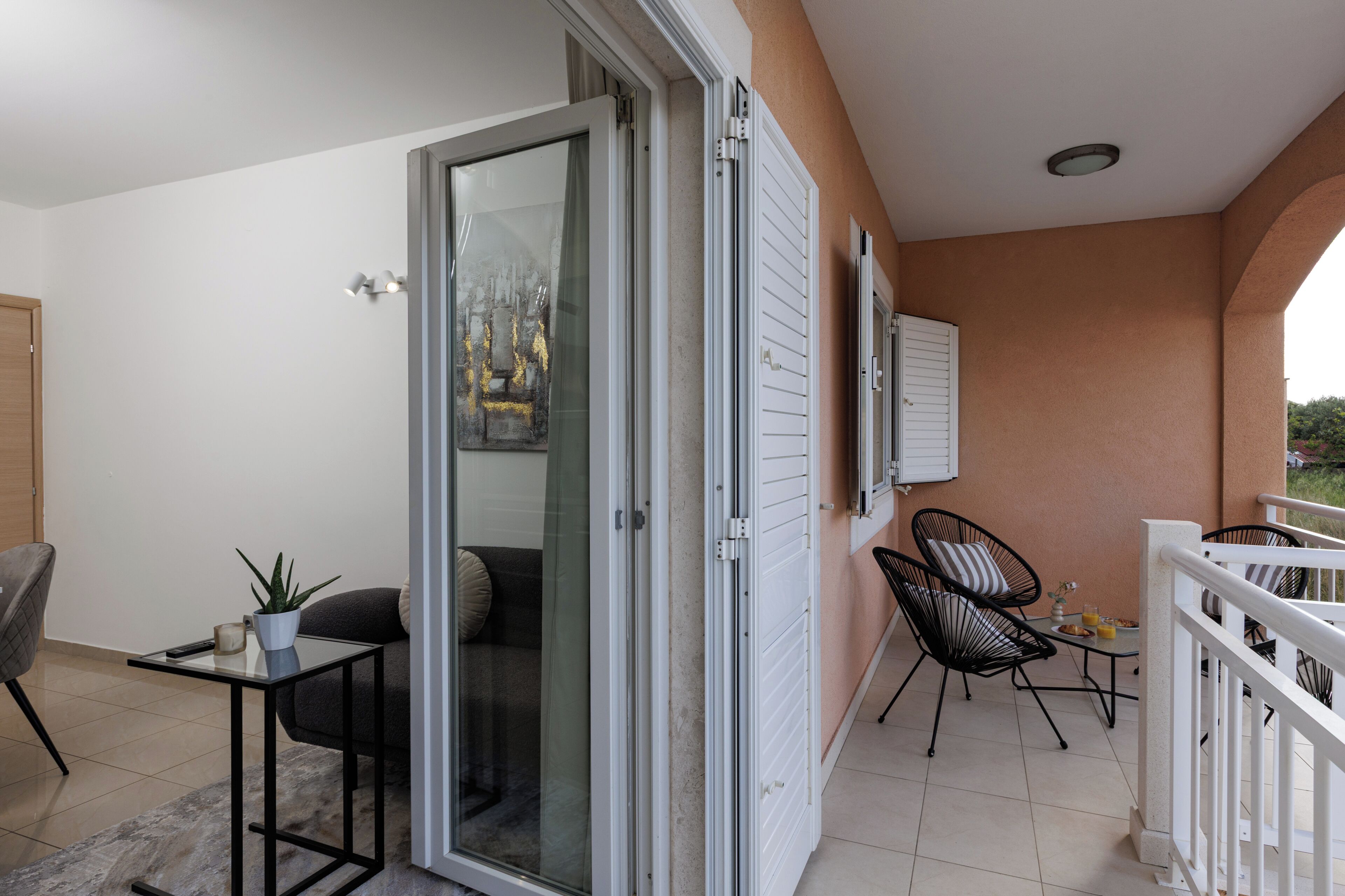 A balcony with a sliding glass door, a small table with a plant, and two chairs.