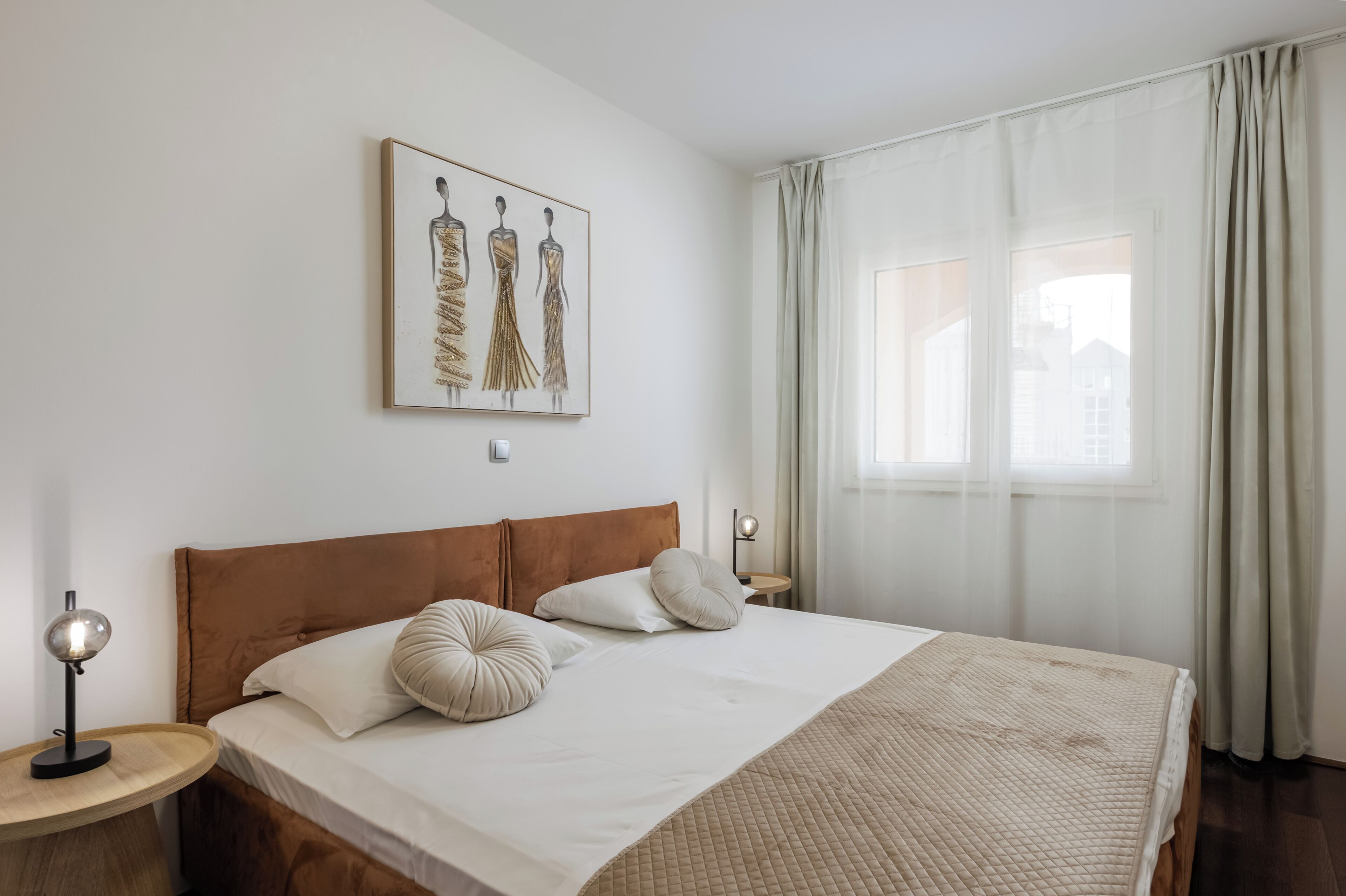 Cama bem arrumada com cabeceira, luminária ao lado e uma obra de arte emoldurada acima.