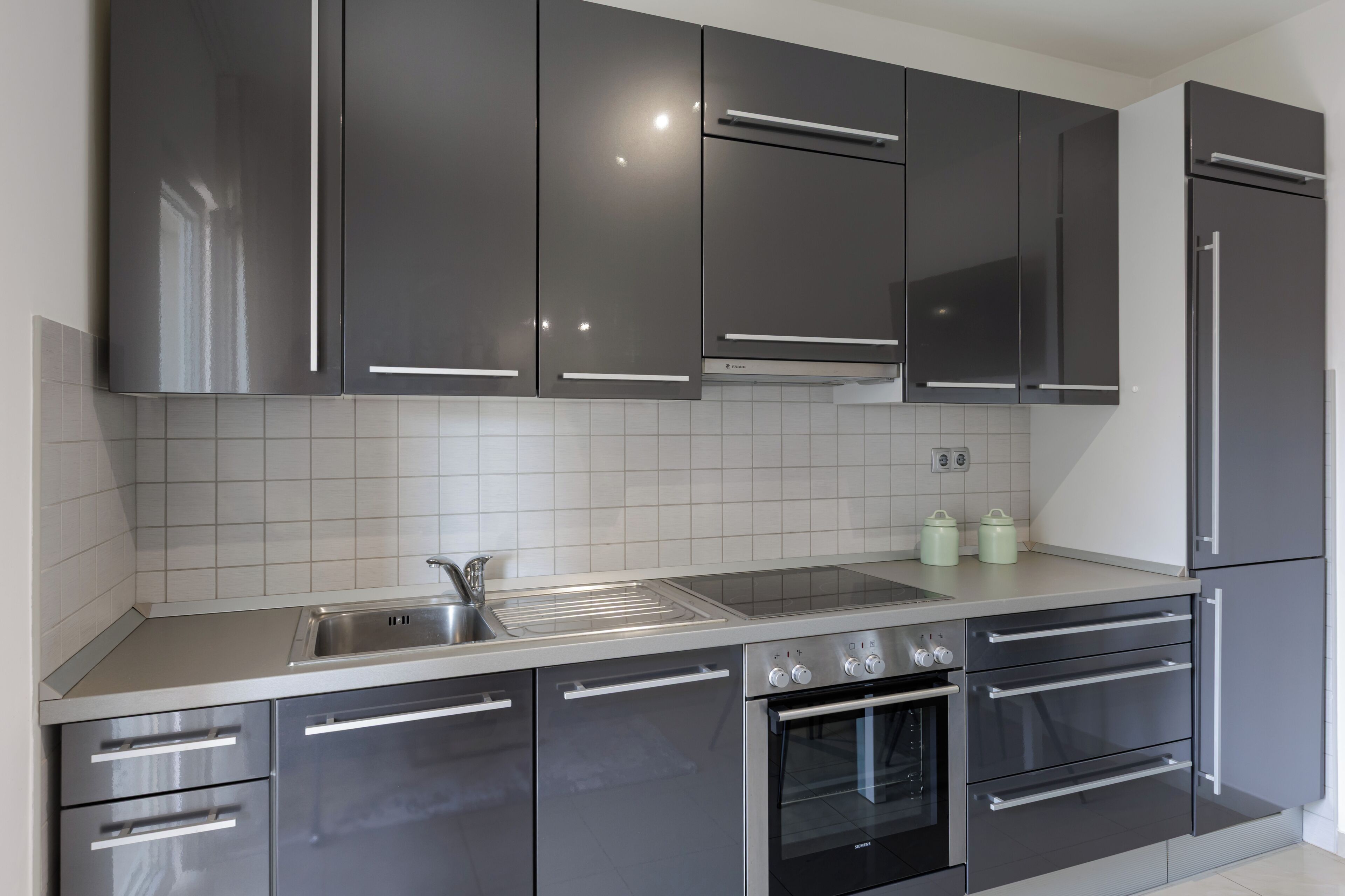 Una cocina moderna con electrodomésticos de acero inoxidable, un lavamanos doble y un salpicadero de azulejos.