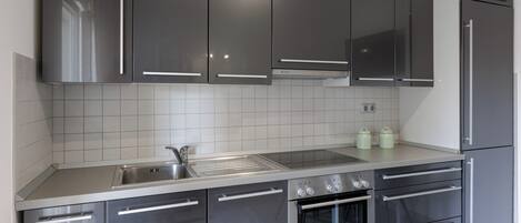 Una cocina moderna con electrodomésticos de acero inoxidable, un lavamanos doble y un salpicadero de azulejos.