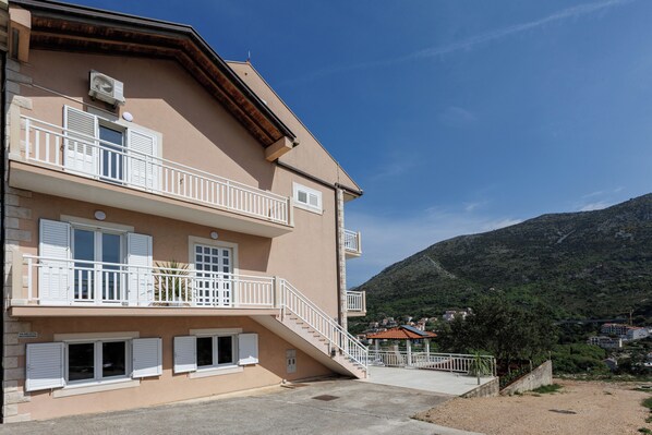 Un edificio de varios pisos con balcones, una escalera y vistas a un paisaje montañoso.