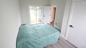 A bedroom with a bed, a sliding glass door to a backyard, and a white door. - Beautiful 3-bedroom house in wonderful Bellingham for your getaway (Bellingham)