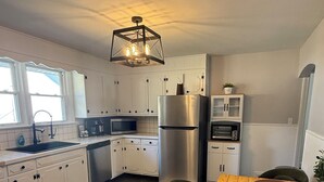 Eine moderne Küche mit weißen Schränken, einem Edelstahlkühlschrank, einem eingebauten Backofen und einem Essbereich mit Holztisch und Stühlen.