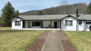 Ein zweistöckiges Haus mit Veranda, Auffahrt und Rasen.
