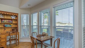 A dining area with a wooden table and chairs, a chessboard, and a wooden cabinet with decorative items. - Charming 3-bedroom cottage with AC in Jamaica Beach (Jamaica Beach)