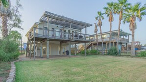 A two-story house with a covered patio, a front deck, and a large lawn. - Charming 3-bedroom cottage with AC in Jamaica Beach (Jamaica Beach)