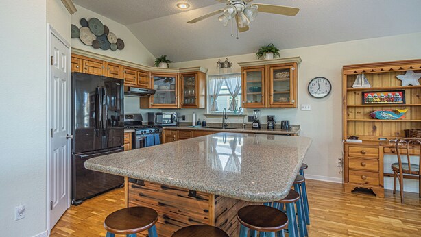 A kitchen with a central island, wooden cabinets, a refrigerator, and a ceiling fan. - Charming 3-bedroom cottage with AC in Jamaica Beach (Jamaica Beach)