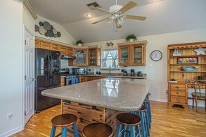 Una cocina con una isla central, armarios de madera, un refrigerador y un ventilador de techo.