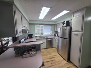 Eine kompakte Küche mit einer Mikrowelle, einem Kühlschrank und einer Kaffeemaschine auf der Arbeitsfläche.