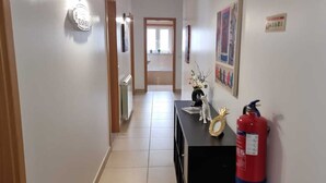 A hallway with a black console table, a fire extinguisher, and a door at the end.
