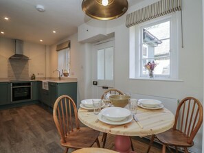 A dining area with a round wooden table, four chairs, and a window with a view of a house.
