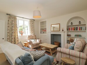 A cozy living room with a sofa, armchair, wooden coffee table, and a fireplace.